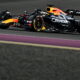 ed Bull Racing Formula One car, painted black with yellow and red accents, races along a track during a night race, with illuminated track boundaries enhancing the high-speed scene.