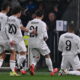 Celebration scene as soccer players rejoice after a goal, featuring Mbappe and his teammates in white kits.