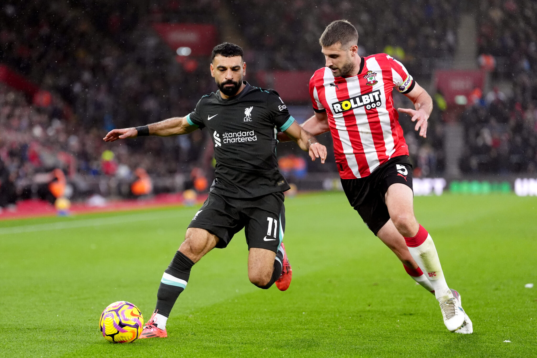 A Liverpool player competes for the ball with a Southampton player during a Premier League match.