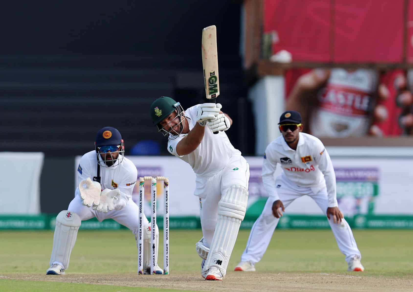 South African batsman in action during a Test match, playing a shot with a straight bat while a Sri Lankan wicketkeeper and slip fielder watch intently, in a game of cricket at St George's Park, Gqeberha.